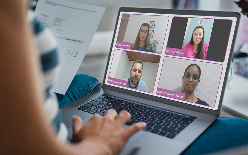 Imagem mostra uma pessoa assistindo a uma formação pelo computador. Na tela, é possível ver a imagem de quatro educadores que estão compartilhando conhecimentos.