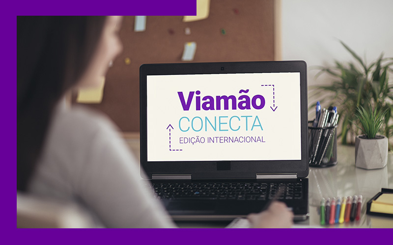 Imagem mostra uma mulher utilizando um notebook. O aparelho está ligado e na tela é possível ver a apresentação do evento Viamão Conecta – Edição Internacional