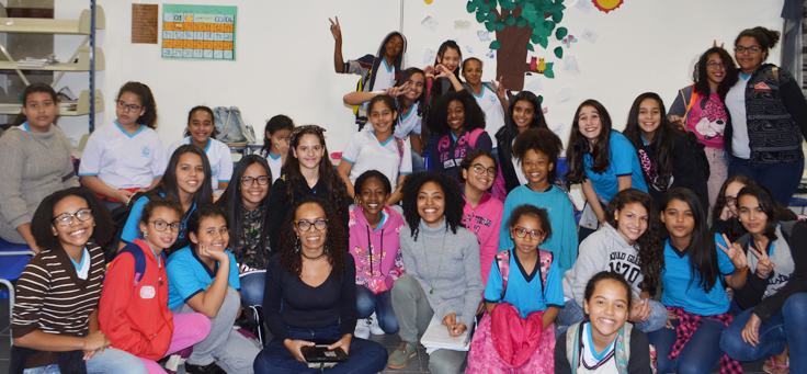 Imagem mostra grupo de meninas e meninos do clube Naturalmente Cacheada posando sentados e em pé