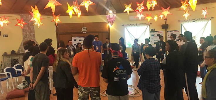 Jovens dos 30 empreendimentos escolhidos para a Imersão do Pense Grande estão em pé formando um círculo sob luminárias em formato de estrelas.