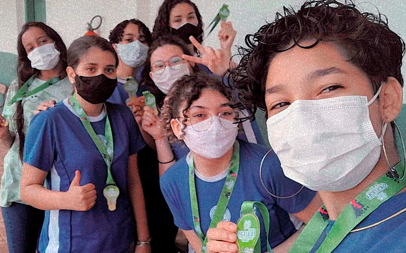 Alunas do Ensino Médio do Colégio Estadual Antônio Francisco Lisboa posam para foto em grupo com as medalhas do seu projeto premiado. Elas estão com o uniforme da escola e máscaras de proteção individual.