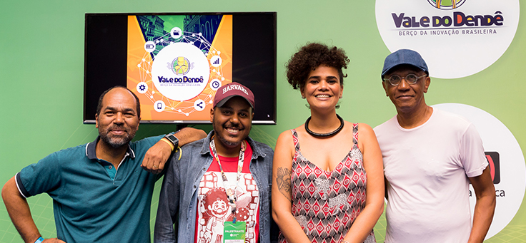 Integrantes do Vale do Dendê posam para foto com o logo da iniciativa ao fundo