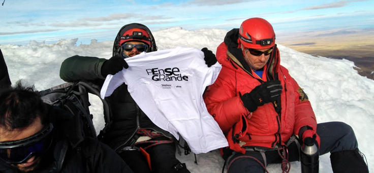 Na imagem, voluntário José Vicente Teixeira Junior veste camisa em homenagem ao Pense Grande em montanha na Bolívia