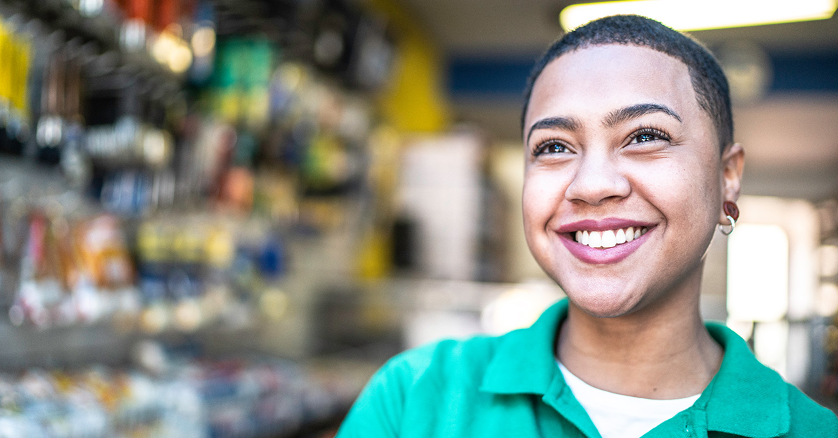 Imagem mostra uma jovem de camisa polo verde sorrindo