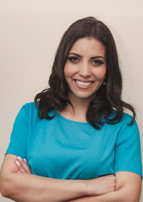 A professora da ETEC Irmã Agostina e vencedora do Demoday Formação de Professores do programa Pense Grande, Renata Borges, está usando blusa azul clara de mangas curtas, cabelos compridos soltos e sorrindo para a foto.