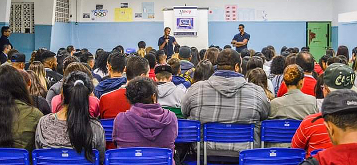 Os jovens Diego e Diogo falam para uma plateia de alunos em uma escola de São Paulo