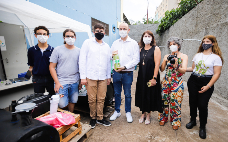 Alunos e professores posam para foto com biogás em uma garrafa pet, resultado do projeto de ciências Tesla.