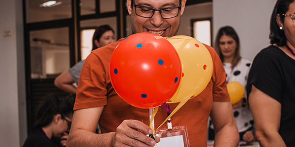 Professor participa de atividade durante a formação de multiplicadores no Mato Grosso do Sul, em que segura dois balões nas cores laranja e amarela