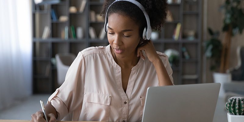 jovem negra estuda diante de caderno e laptop.