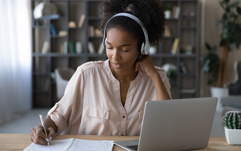 jovem negra estuda diante de caderno e laptop.
