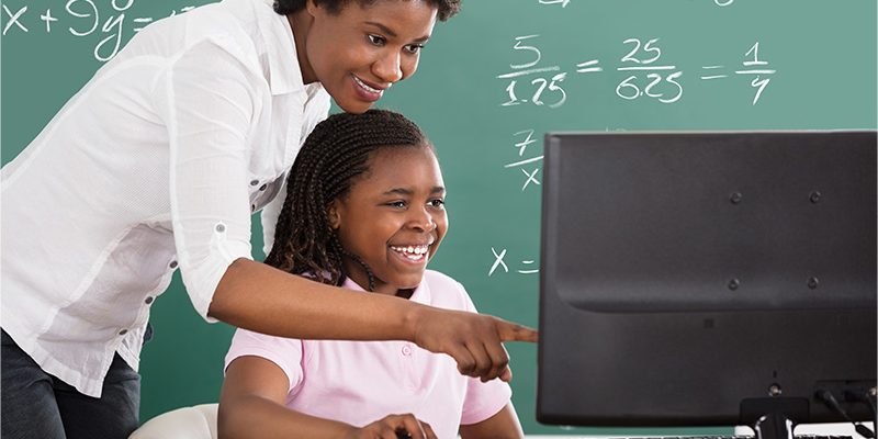 Professora e aluna diante de computador.