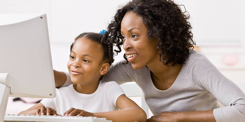 mãe e filha diante de computador