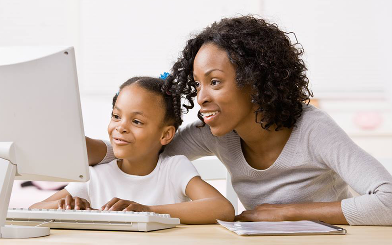 mãe e filha diante de computador
