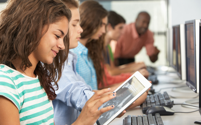 Aluna utiliza tablet durante aula na sala de informática da escola.