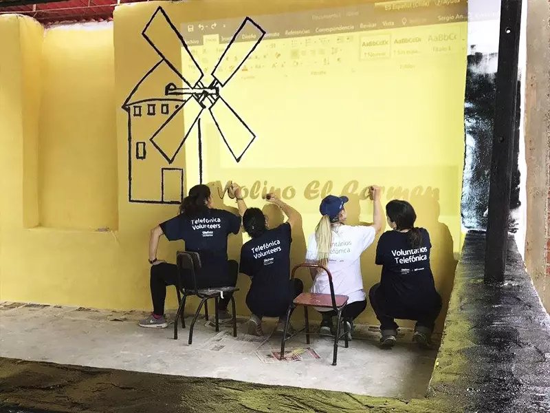Voluntários pintam parede em Escola Molino de Carmen, no Peru, tem parede pintada com nuvens e arco-íris