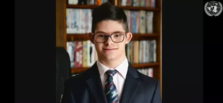 Jovem Samuel, que tem Síndrome de down, está usando terno e gravata em cerimônia anual da ONU sobre educação inclusiva.